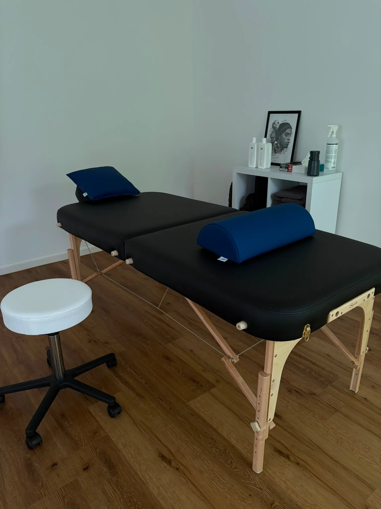 Behandlungsliege der Lumax-Praxis mit Lagerungsrolle und Hocker