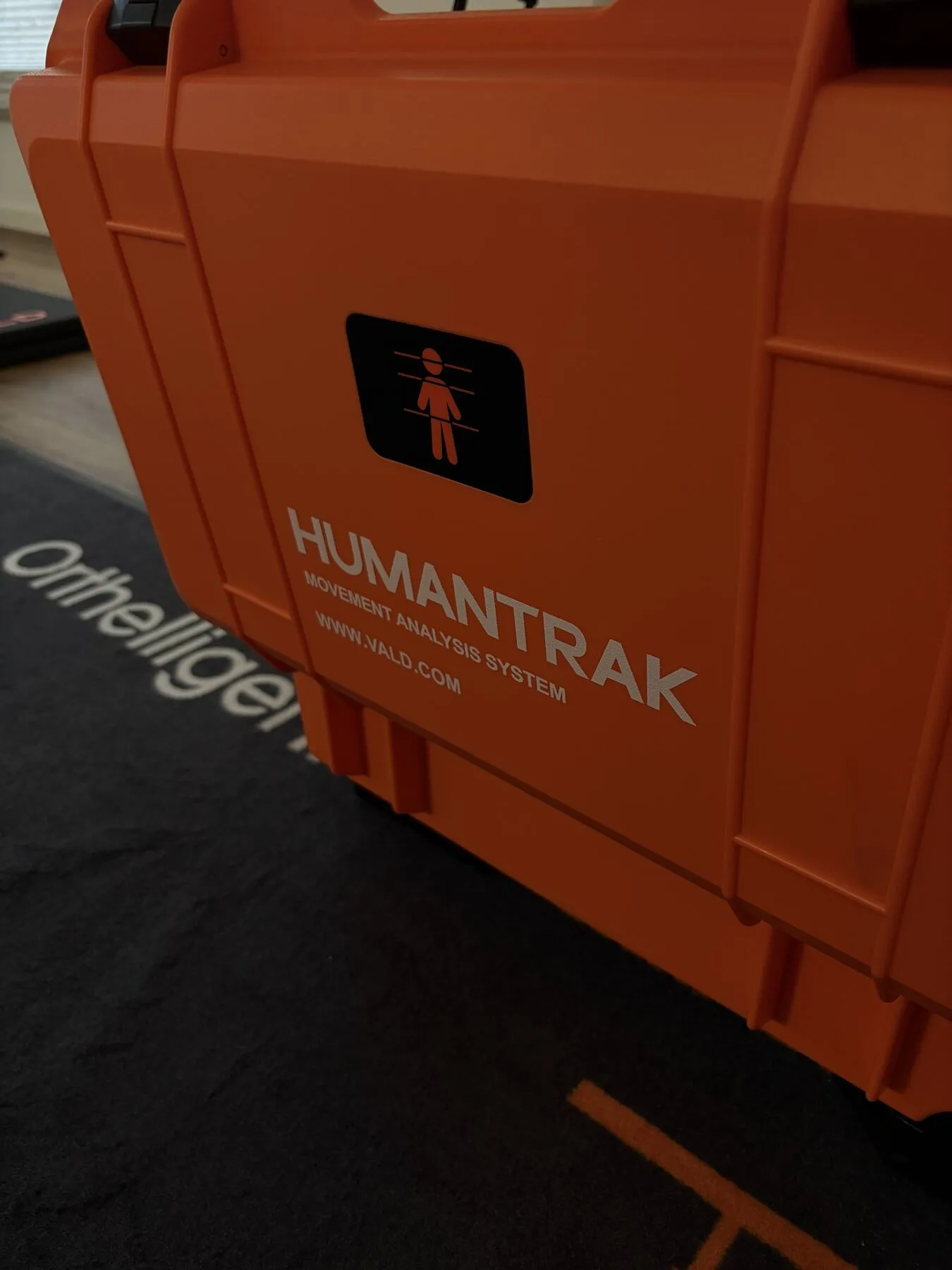 Oranger HumanTrak-Transportkoffer auf der Messmatte